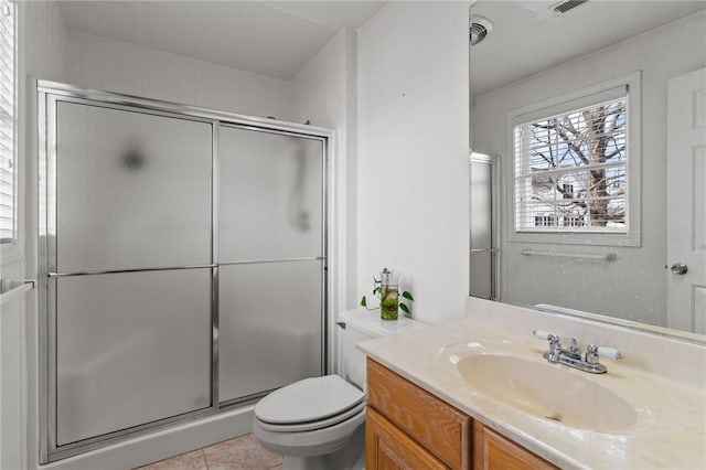 bathroom featuring a shower with door, vanity, tile patterned floors, and toilet