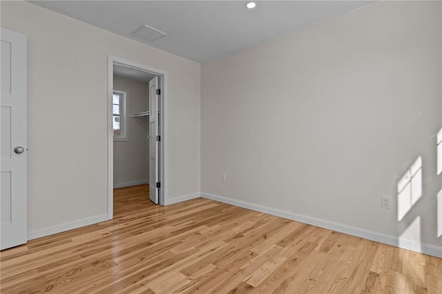 unfurnished bedroom featuring a walk in closet and light hardwood / wood-style floors