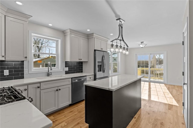 kitchen with a kitchen island, tasteful backsplash, sink, hanging light fixtures, and stainless steel appliances