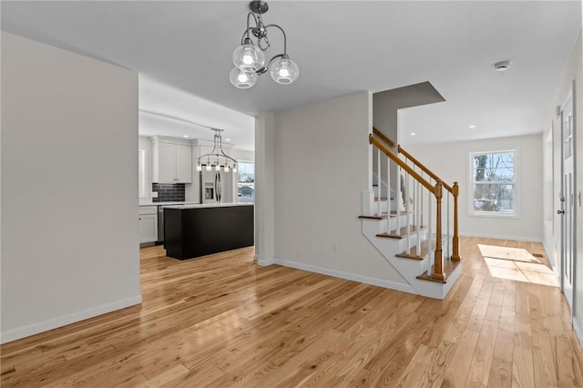 interior space with an inviting chandelier, a wealth of natural light, and light wood-type flooring