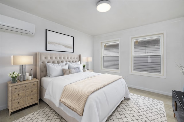 bedroom featuring baseboards, an AC wall unit, and light wood-style floors