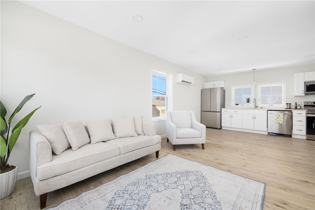 living room with a wall unit AC and light wood-style floors