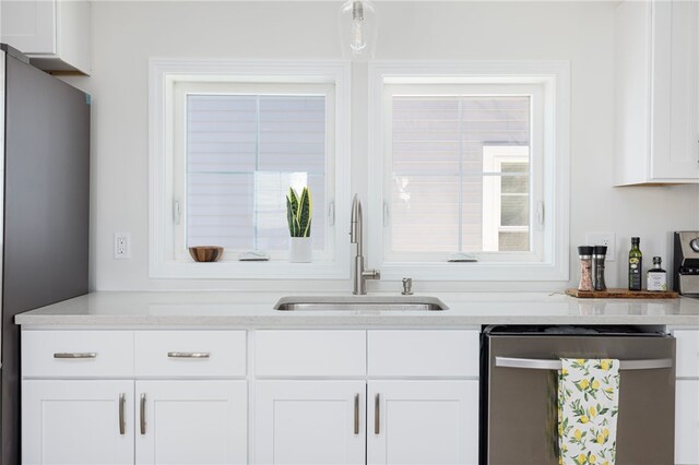 kitchen featuring light countertops, appliances with stainless steel finishes, a sink, and white cabinetry