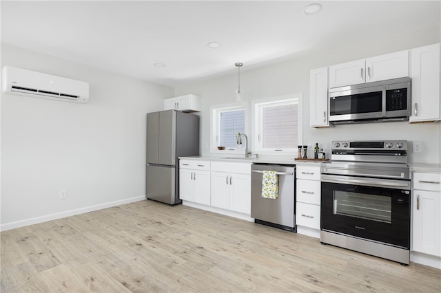 kitchen featuring light countertops, appliances with stainless steel finishes, white cabinetry, a sink, and a wall mounted air conditioner