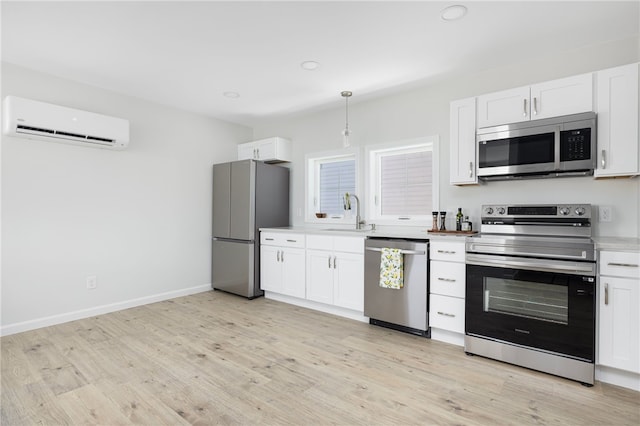 1 Nobert St Unit 1, Warren, RI 02885 - kitchen featuring stainless steel appliances, a wall unit AC, a sink, light wood-type flooring, and white cabinets