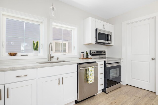 1 Nobert St Unit 1, Warren, RI 02885 - kitchen featuring stainless steel appliances, a sink, light wood-style flooring, white cabinets, and pendant lighting