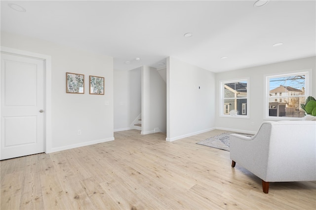 living area with light wood-style floors, baseboards, and stairs