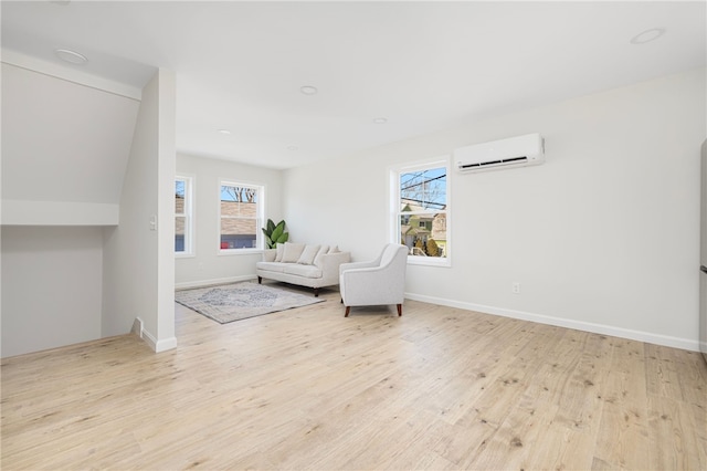 sitting room featuring a wall unit AC, light wood-style flooring, and baseboards