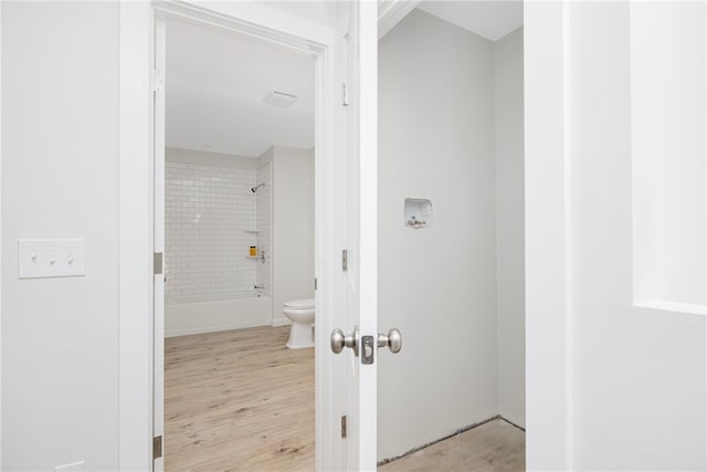 bathroom with  shower combination, toilet, and wood finished floors