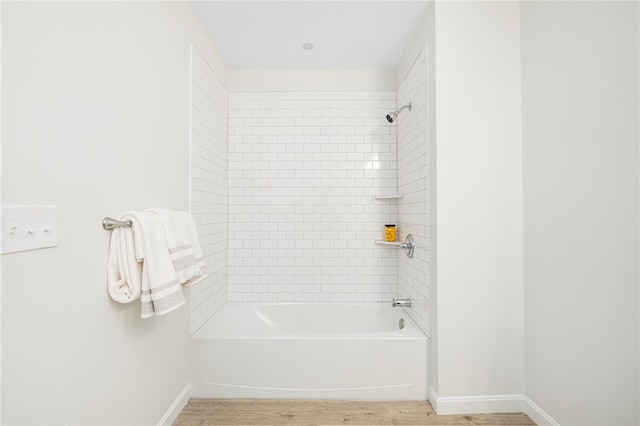 bathroom with wood finished floors, bathtub / shower combination, and baseboards