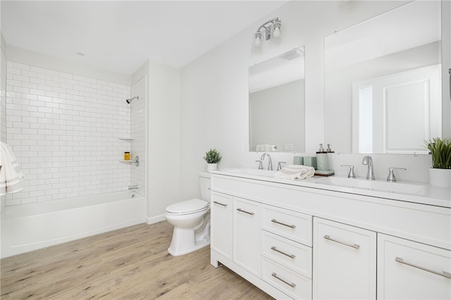 full bath with double vanity, wood finished floors, a sink, and washtub / shower combination