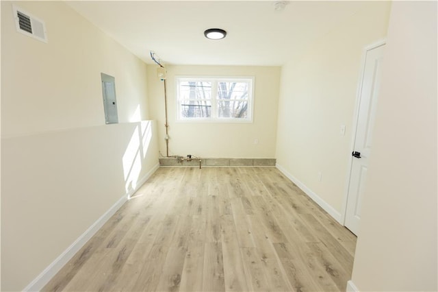 unfurnished room featuring electric panel and light hardwood / wood-style floors