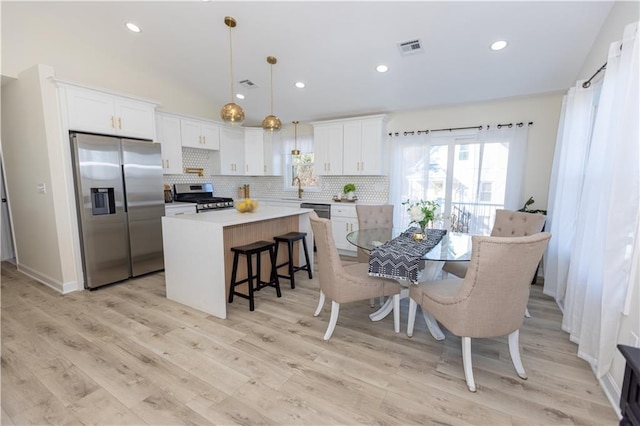 kitchen with pendant lighting, sink, stainless steel appliances, a center island, and white cabinets