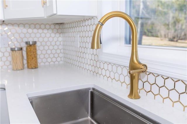 details featuring sink, decorative backsplash, and white cabinets