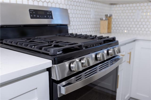 room details with tasteful backsplash, stainless steel gas range, and white cabinets