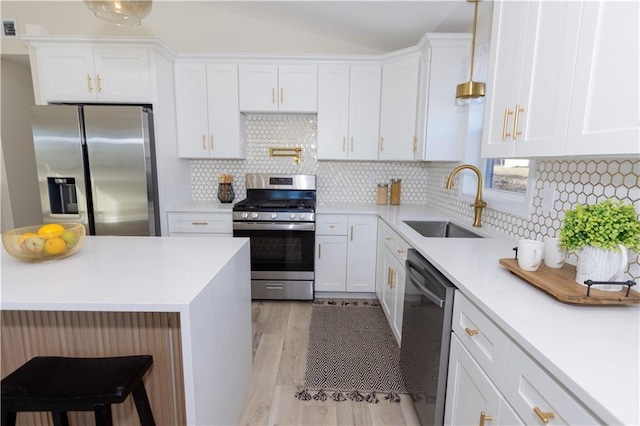 kitchen with appliances with stainless steel finishes, sink, white cabinets, backsplash, and hanging light fixtures