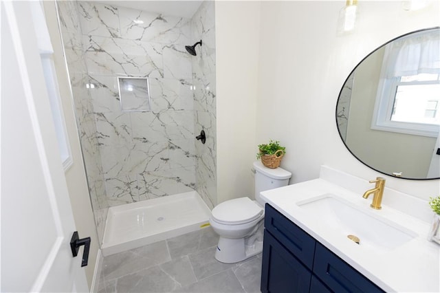 bathroom with vanity, toilet, and a tile shower