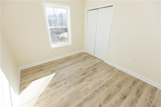 unfurnished bedroom with a closet and light wood-type flooring