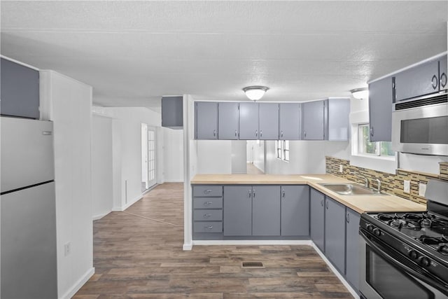 kitchen with sink, range with gas cooktop, white refrigerator, gray cabinets, and backsplash