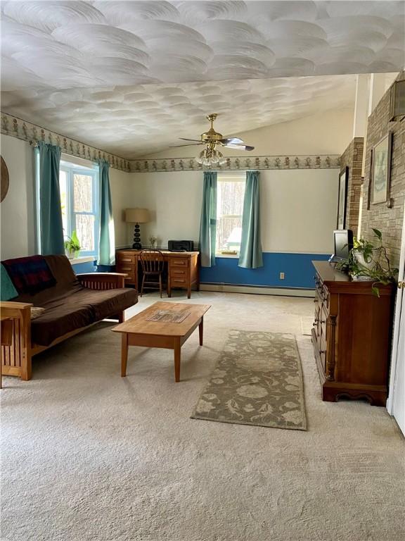 living area with lofted ceiling, plenty of natural light, light colored carpet, and a baseboard radiator