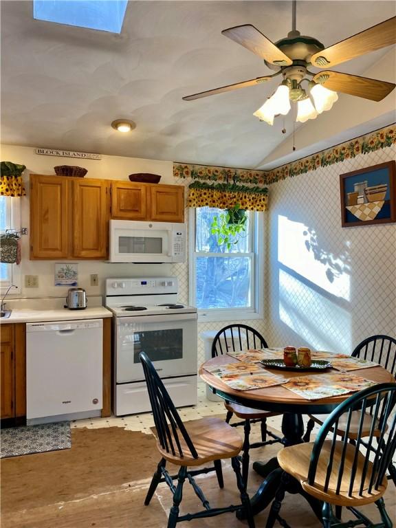 kitchen featuring ceiling fan, lofted ceiling with skylight, and white appliances