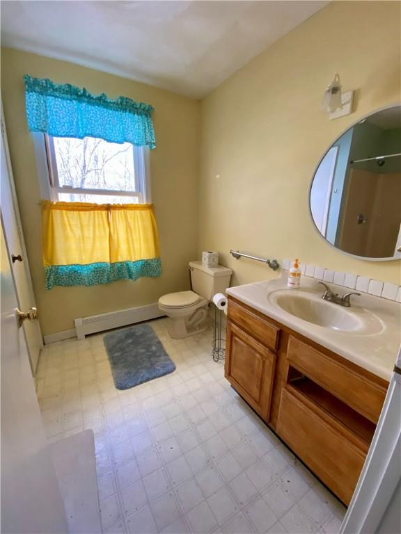 bathroom featuring a baseboard radiator, toilet, vanity, and walk in shower