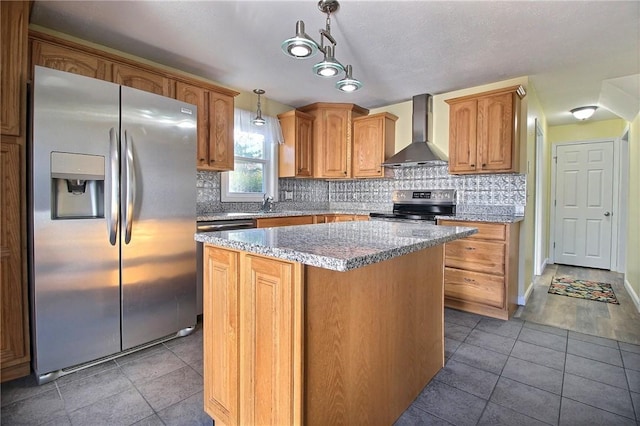 kitchen featuring appliances with stainless steel finishes, decorative light fixtures, a center island, light stone counters, and wall chimney range hood