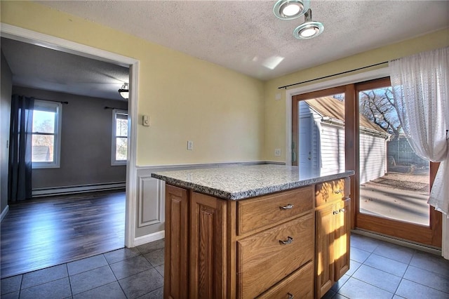 kitchen featuring dark tile patterned flooring, a baseboard radiator, a center island, and a textured ceiling