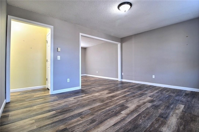 empty room featuring a textured ceiling and dark hardwood / wood-style flooring