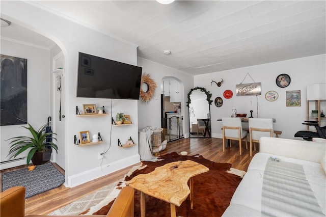 living room with a baseboard heating unit, crown molding, and wood-type flooring