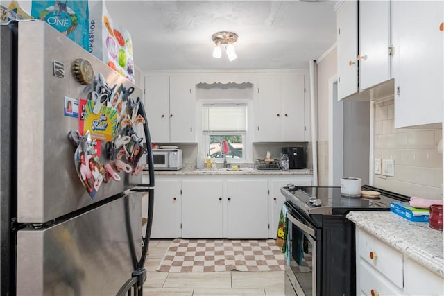 kitchen with sink, white cabinetry, electric range oven, stainless steel fridge, and decorative backsplash