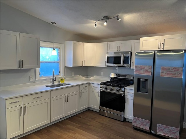 kitchen with hanging light fixtures, stainless steel appliances, light countertops, white cabinetry, and a sink