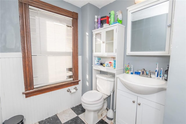 bathroom featuring vanity, wooden walls, and toilet