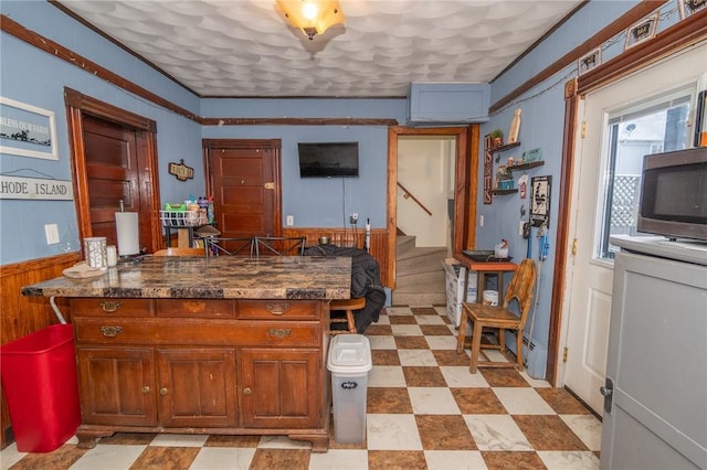 kitchen featuring crown molding, wooden walls, and kitchen peninsula