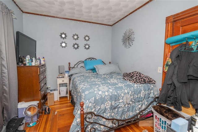 bedroom featuring crown molding and wood-type flooring