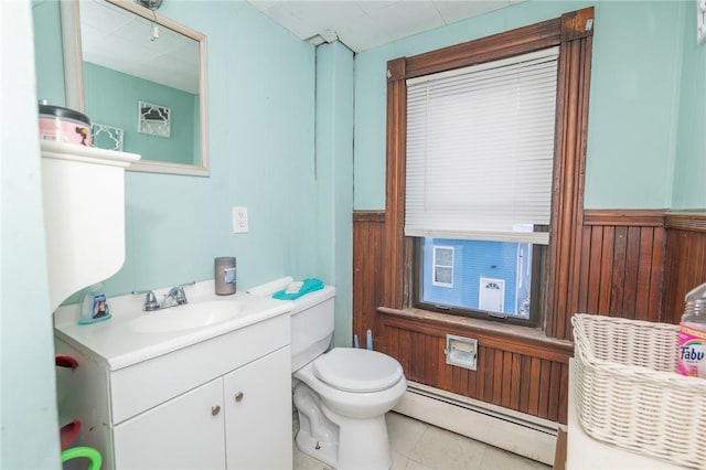 bathroom featuring wood walls, a baseboard radiator, vanity, and toilet