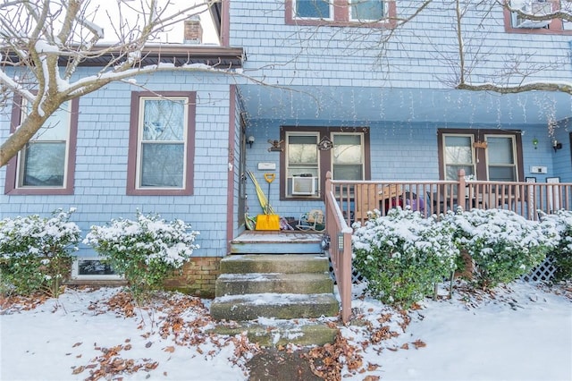 snow covered property entrance with covered porch