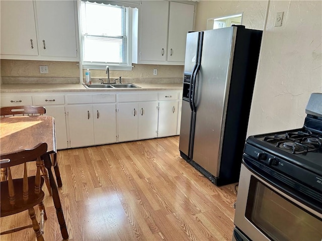 kitchen featuring stainless steel appliances, white cabinetry, sink, and light hardwood / wood-style floors