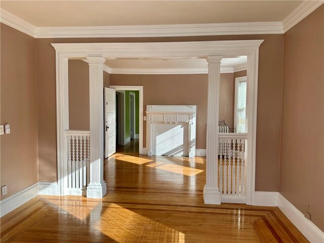 hall featuring decorative columns, crown molding, and hardwood / wood-style floors