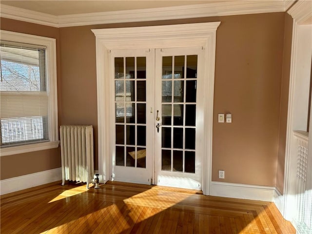 doorway with crown molding, wood-type flooring, radiator heating unit, and french doors