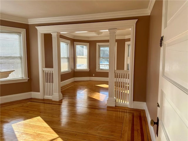 spare room with hardwood / wood-style flooring, ornamental molding, and decorative columns