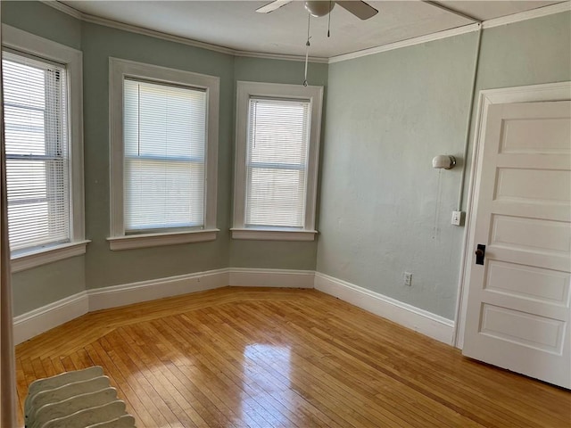 empty room featuring ornamental molding, ceiling fan, and light wood-type flooring