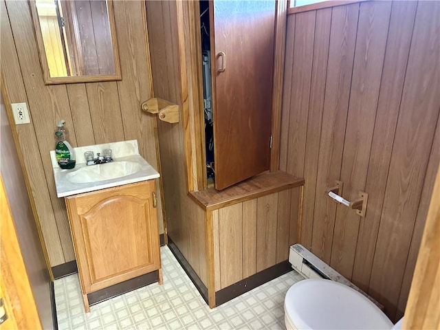 bathroom featuring vanity, wooden walls, and toilet