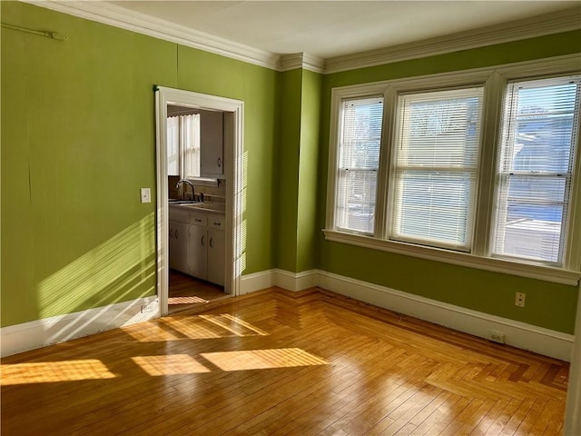 spare room with ornamental molding, sink, light parquet floors, and a wealth of natural light