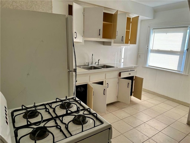 kitchen with white cabinetry, sink, light tile patterned flooring, and white appliances