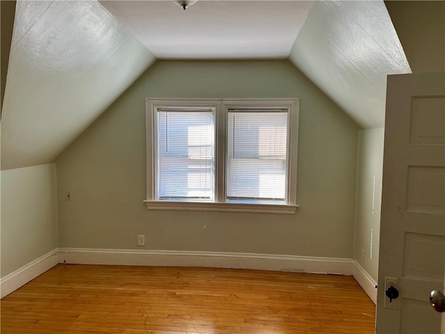 additional living space featuring light hardwood / wood-style flooring and vaulted ceiling