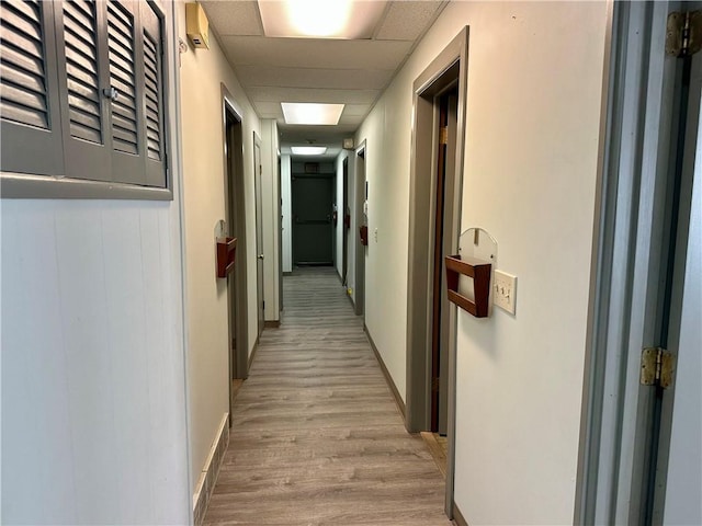 corridor with light hardwood / wood-style floors and a drop ceiling