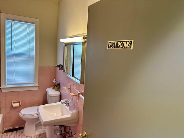 bathroom featuring toilet, tile patterned flooring, sink, and tile walls