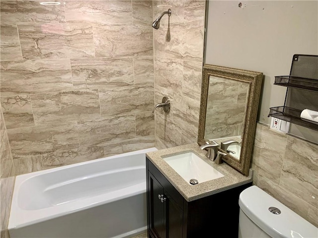 full bathroom with tiled shower / bath, vanity, toilet, and tile walls