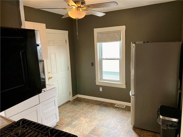 kitchen featuring ceiling fan, stainless steel fridge, and white cabinets